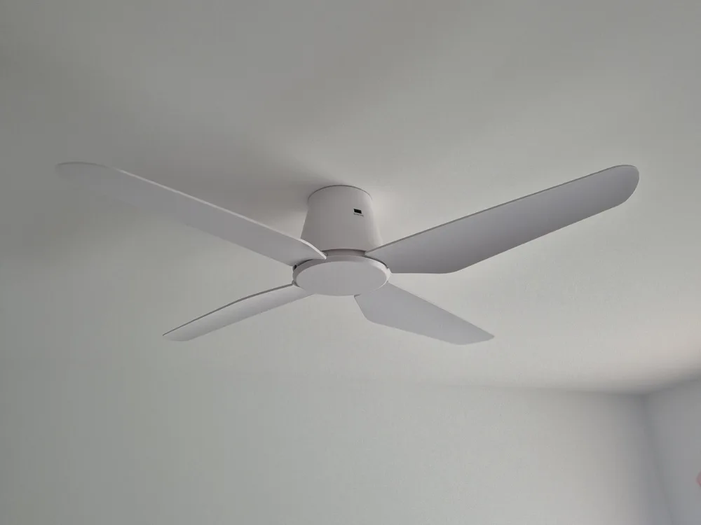 Low-profile white ceiling fan installed in a bedroom