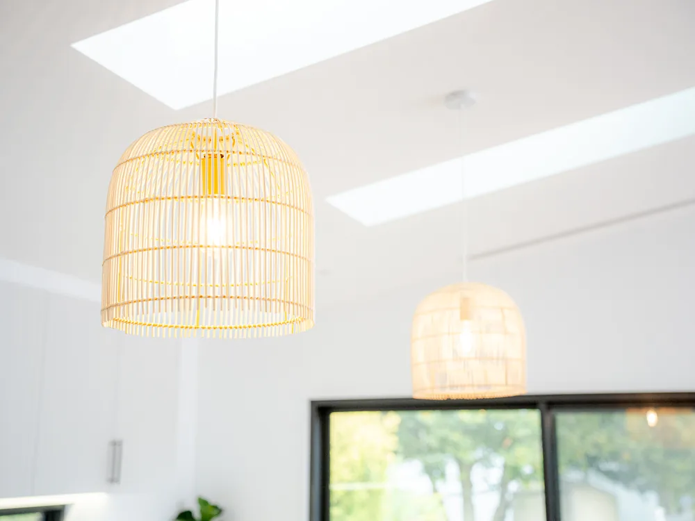 Rattan pendant lights installed over a bright open-plan living space